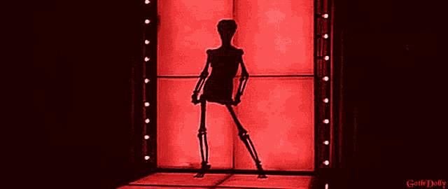 a skeleton is hanging upside down in front of a red wall with the words gothic dolly written on the bottom