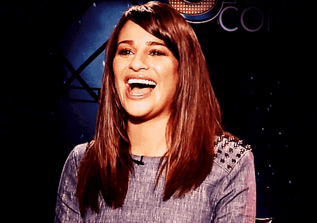 a woman laughing in front of a sign that says co