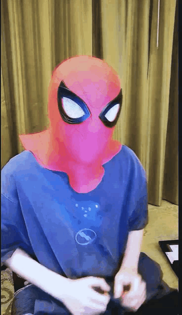 a person wearing a spiderman mask is sitting on a chair