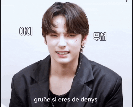 a young man in a black jacket is making a funny face while talking in a foreign language .