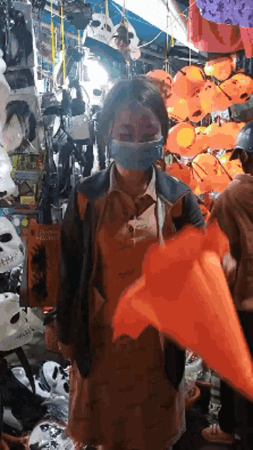 a woman wearing a mask is standing in front of a store that sells halloween decorations
