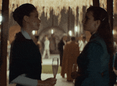 two women standing next to each other one holding a glass of wine