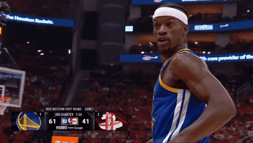 a basketball player pointing at the scoreboard which says 7:30 on it