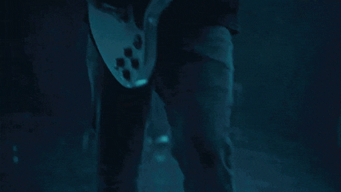 a man is playing a white guitar in a dark room