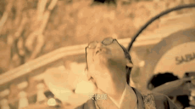 a man in a kimono and glasses is looking up at the sky .