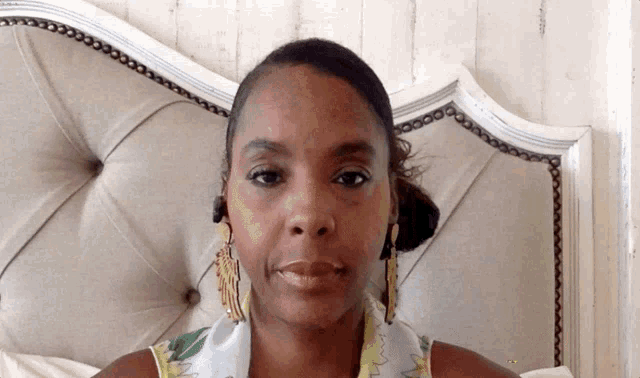 a woman with a scarf around her neck is sitting in front of a bed