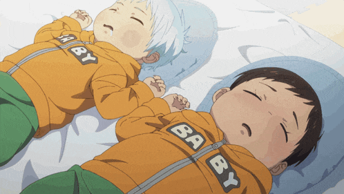 two baby boys laying on a bed wearing jackets that say baby on them