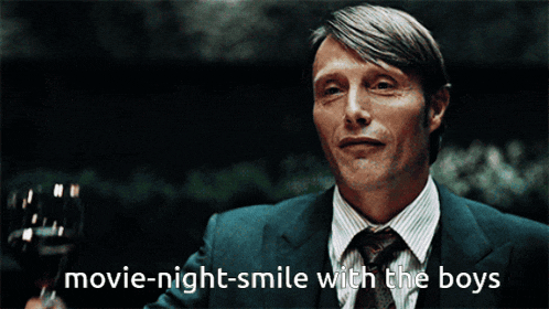 a man in a suit and tie holding a glass of wine with the words movie-night-smile with the boys written below him