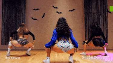 three women are dancing in front of a wall with bats on it and the words they killed it on the bottom