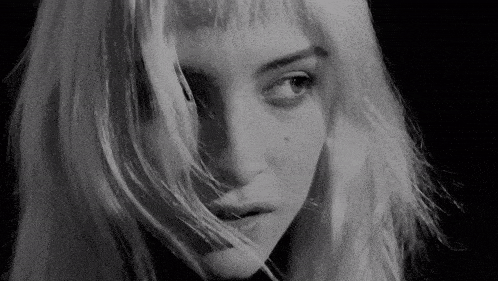 a close up of a woman 's face with her hair blowing in the wind