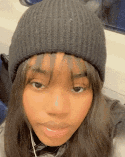 a girl wearing a black beanie and headphones is looking at the camera .