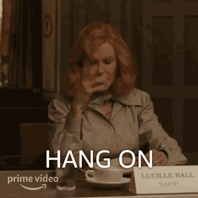 a woman is sitting at a table with a sign that says lucille ball lucy