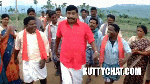 a man in a red shirt stands in front of a crowd of people with the website kuttychat.com written on the bottom