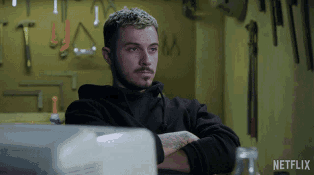 a man in a black hoodie sits with his arms crossed in a netflix ad