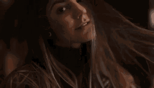 a woman with long hair is wearing a black turtleneck sweater and earrings .