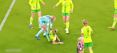 a group of women are playing soccer on a field and one of them is laying on the ground .