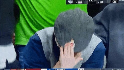 a person covering their face with a towel while watching a cbs game