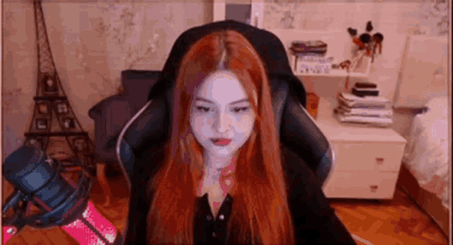 a woman with red hair is sitting in a chair in front of a computer screen .