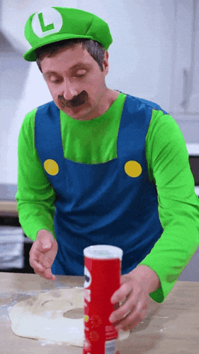 a man dressed in a luigi costume holds a potato chip