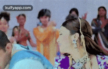 a woman is dancing in front of a crowd of people in a room .