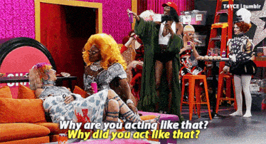 a group of drag queens are sitting on a couch in a room .