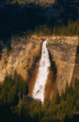 a waterfall surrounded by trees and rocks in the mountains