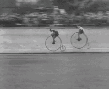 a black and white photo of a man riding a penny farthing