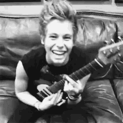 a young man is sitting on a couch playing a guitar .