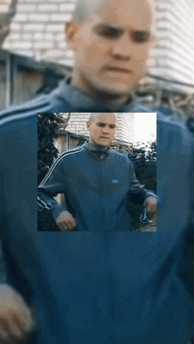 a man in a blue adidas jacket is standing in front of a building .