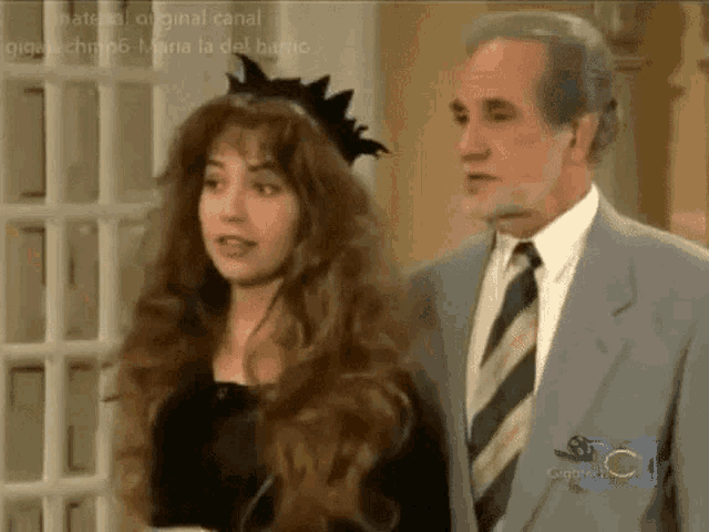 a man in a suit and tie stands next to a woman in a black dress .