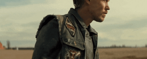 a man wearing a leather vest with patches on the sleeves