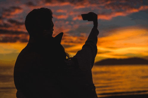 a person taking a picture of a sunset with a phone