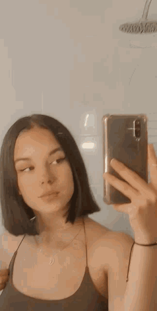 a woman is taking a selfie in front of a mirror .