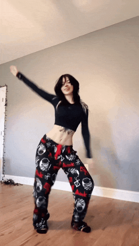 a woman in a black top and skull pajamas is dancing