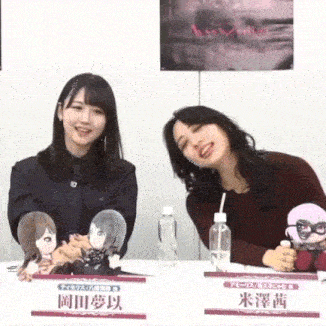 two women are sitting at a table holding stuffed animals and drinking water .