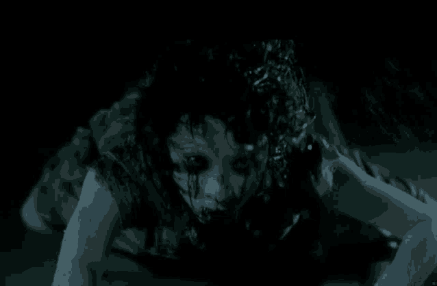 a ghost is crawling on the floor in the dark with blood coming out of her eyes .