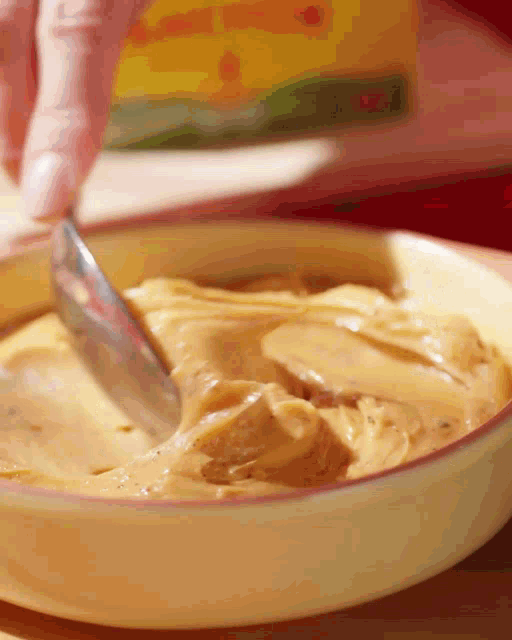 a bowl of peanut butter is being stirred with a knife