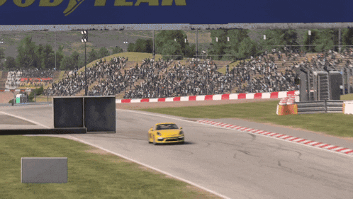 a yellow car is driving down a race track in front of a sign that says good year