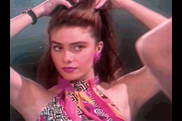 a woman is wearing a pink scarf around her neck and earrings .