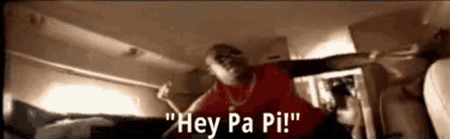 a man in a red shirt is standing in a room and saying hey pa pi !
