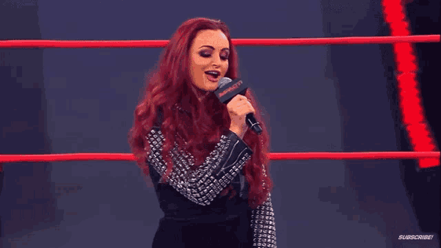 a woman is singing into a microphone in a wrestling ring .