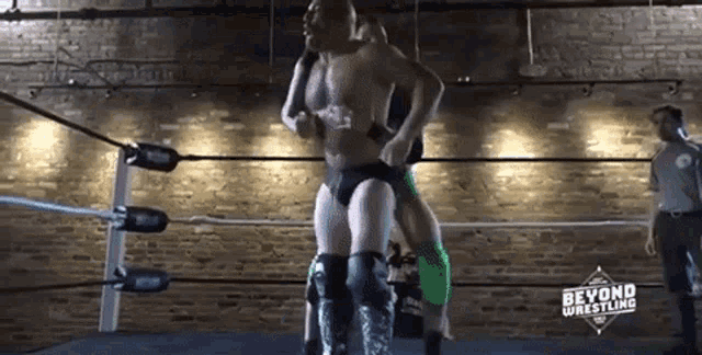 a man is wrestling another man in a wrestling ring while a referee looks on .