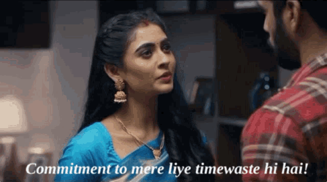 a woman in a blue saree is talking to a man in a red plaid shirt