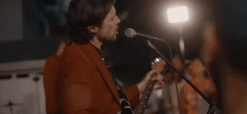 a man in a red suit sings into a microphone