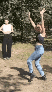 a woman in a black tank top is dancing in a park