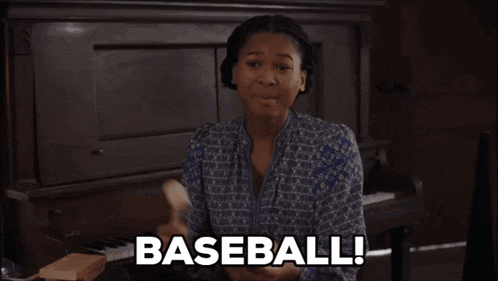 a woman sitting in front of a piano holding a book that says baseball