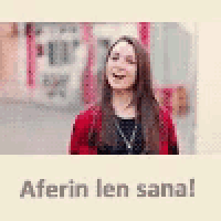 a woman in a red sweater is laughing in front of a building and the words aferin len sana .