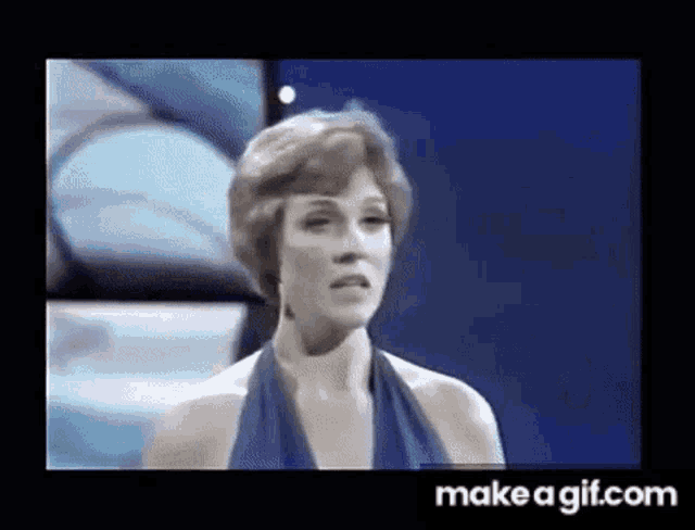 a woman in a blue dress is standing on a stage in front of a blue background .