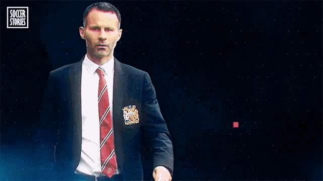 a man in a suit and tie stands in front of a blue background that says soccer stories