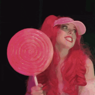 a woman with red hair holds a pink lollipop